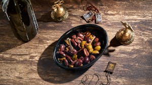 Assorted olives in a black bowl with decorative brass items, creating a rustic feel.