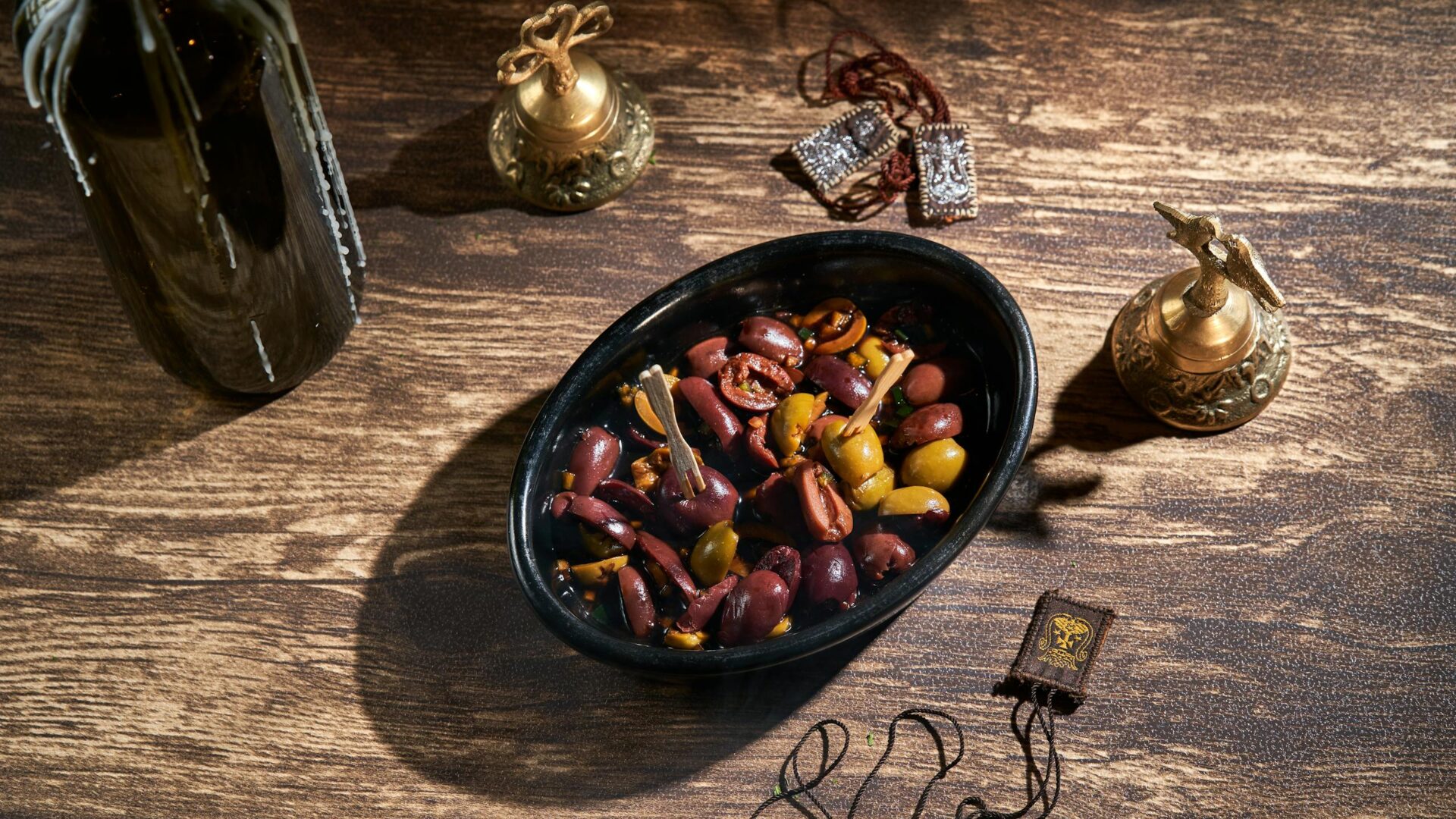 Assorted olives in a black bowl with decorative brass items, creating a rustic feel.