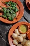 Assorted Spanish tapas with Padron peppers and sauces served on a rustic outdoor table.