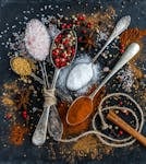 Assorted spices and seasonings arranged creatively on a dark surface, showcasing culinary art.