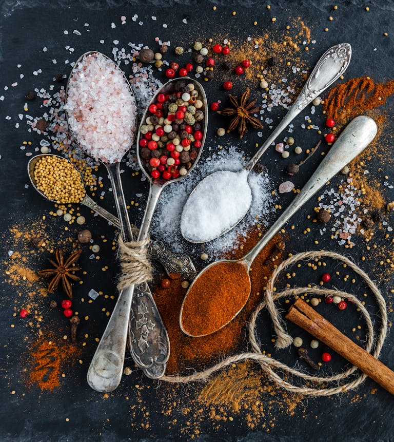 Assorted spices and seasonings arranged creatively on a dark surface, showcasing culinary art.