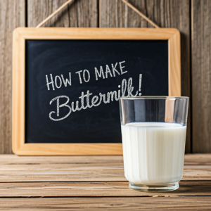 Glass of buttermilk in front of a chalkboard sign.