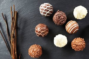 Assorted chocolate truffles on slate with twigs.
