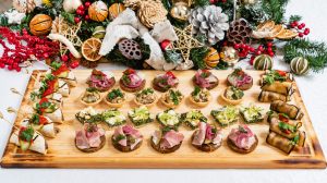 Assorted Christmas appetizer bites arranged on a wooden serving board with festive decorations.