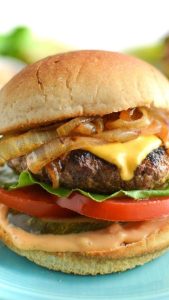 Classic cheeseburger with melted cheese, onions, tomato, lettuce, and pickles.