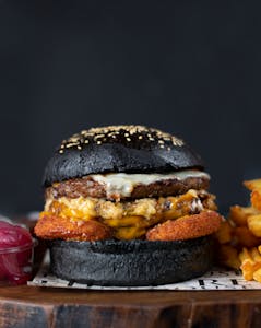 Close-up of a gourmet burger with a black bun and fries. Perfect for food photography.