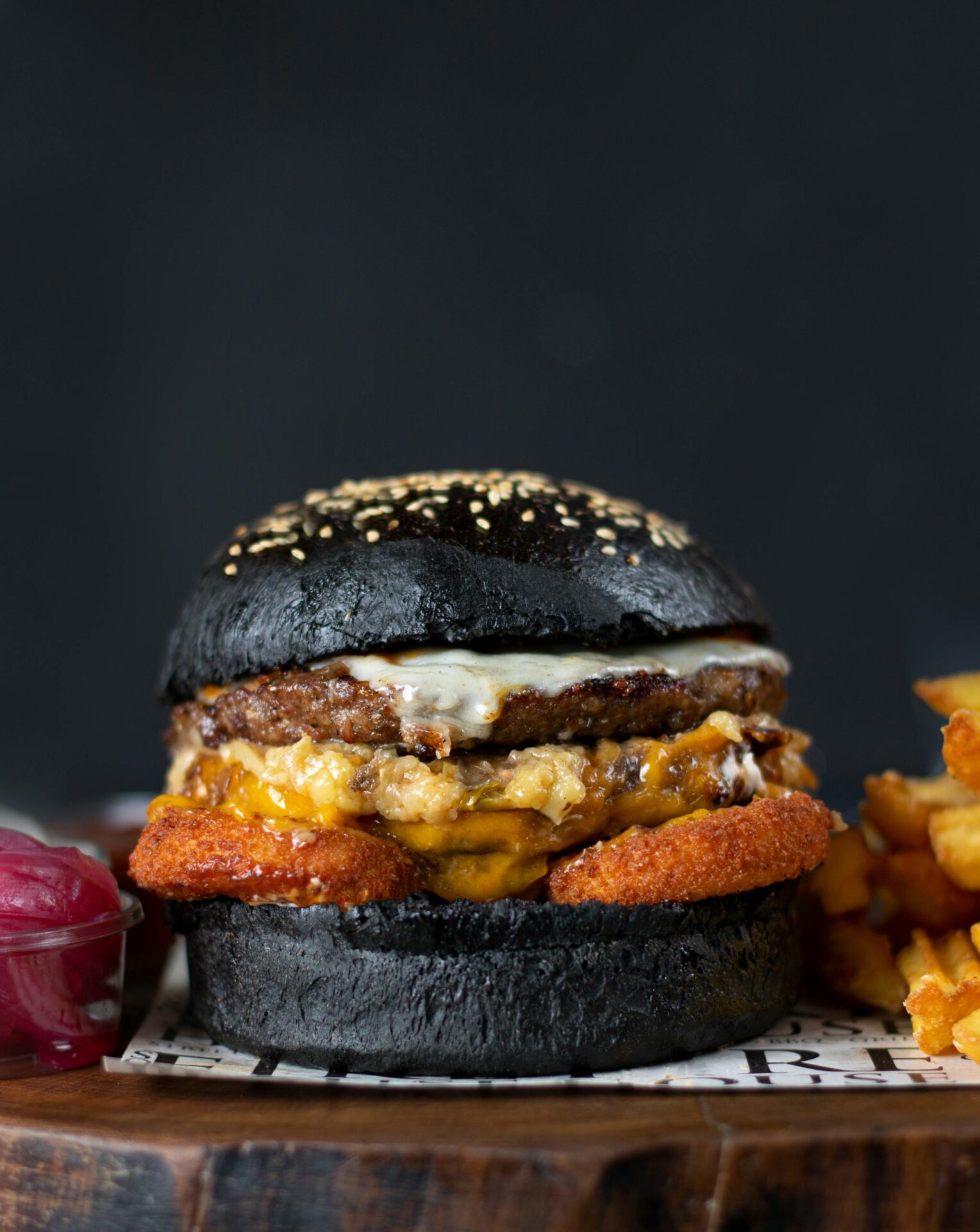 Close-up of a gourmet burger with a black bun and fries. Perfect for food photography.