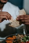 Close-up of a man breaking pita bread during an indoor iftar meal.
