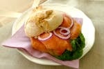 Close-up of a salmon sandwich with fresh vegetables on a ceramic plate, perfect for a healthy meal.