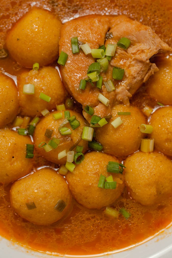 Close-up of a traditional Paraguayan chicken stew with dumplings and fresh herbs.