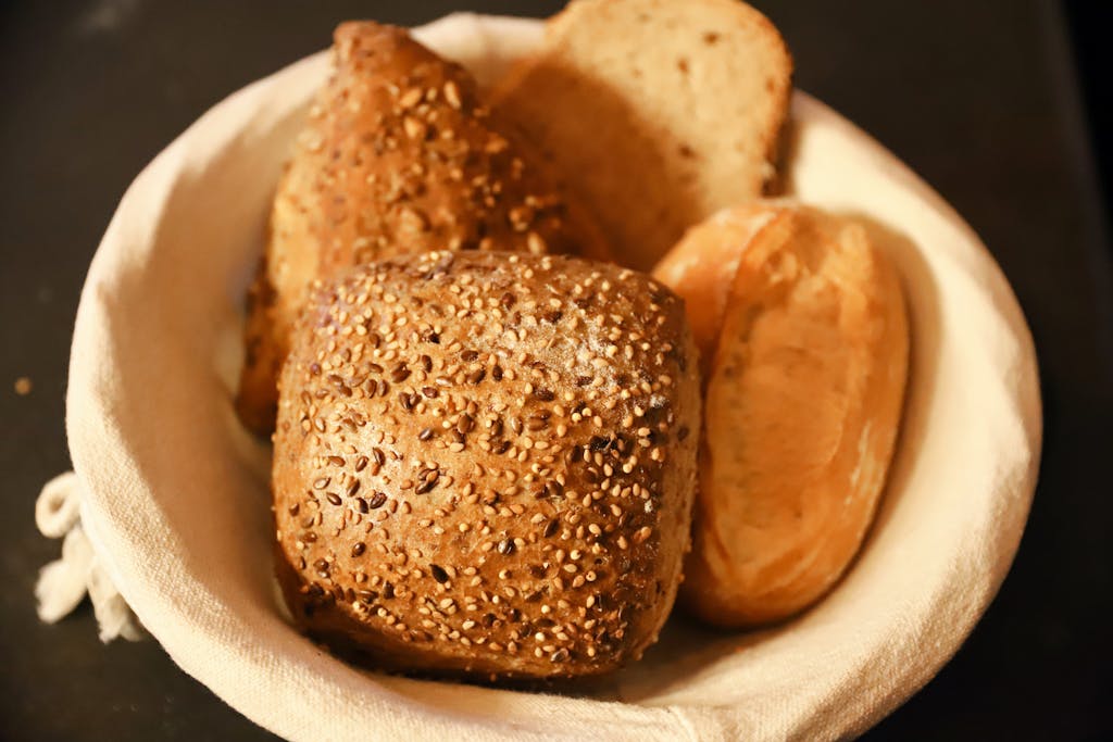 Close-up of assorted freshly baked bread rolls in a basket, perfect for breakfast or brunch.