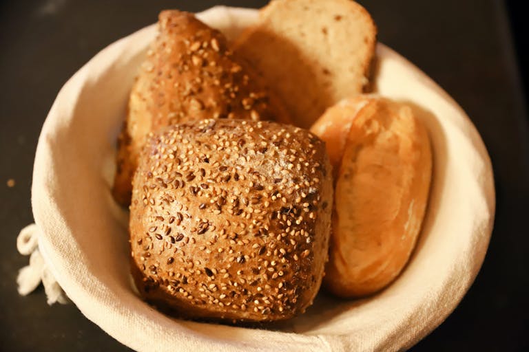 Close-up of assorted freshly baked bread rolls in a basket, perfect for breakfast or brunch.