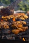 Close-up of barbecue chicken cooking on a grill, surrounded by smoky flames, perfect for summer parties.