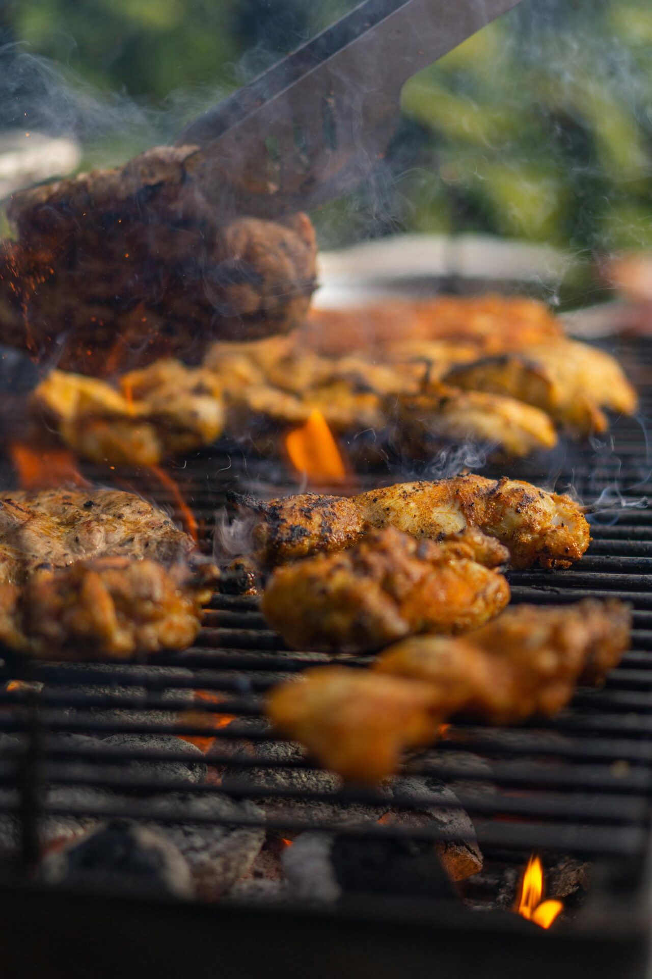 Close-up of barbecue chicken cooking on a grill, surrounded by smoky flames, perfect for summer parties.