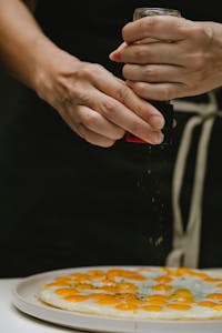 Close-up of chef seasoning a gourmet egg dish with pepper, showcasing culinary expertise.