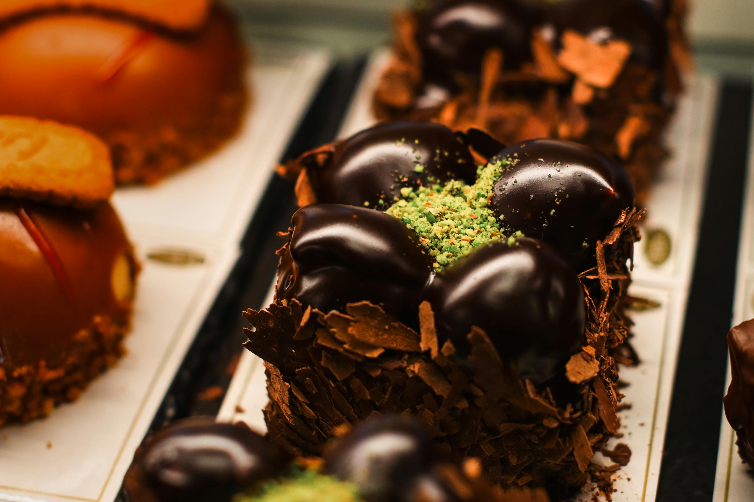 Close-up of exquisite chocolate desserts with vibrant toppings in a high-end bakery setting.