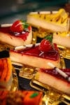 Close-up of gourmet strawberry cheesecake slices with vibrant toppings displayed on golden trays.
