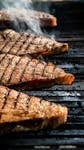 Close-up of juicy steaks on a grill with smoke, showcasing ideal grill marks.