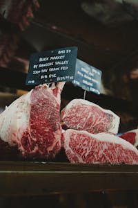 Close-up of premium rib eye steaks displayed at a retail market with signage.