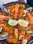 Close-up of traditional Spanish seafood paella with shrimp, mussels, and lemon slices.