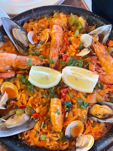 Close-up of traditional Spanish seafood paella with shrimp, mussels, and lemon slices.