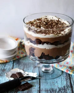 Layered chocolate trifle in a glass bowl topped with whipped cream and chocolate shavings.