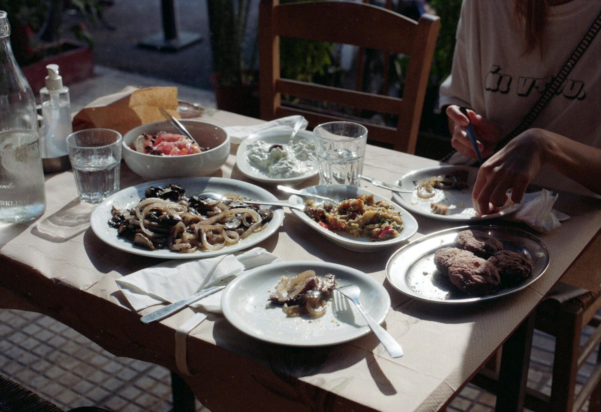 Cozy outdoor dining with a variety of Greek dishes shared among friends on a summer day.