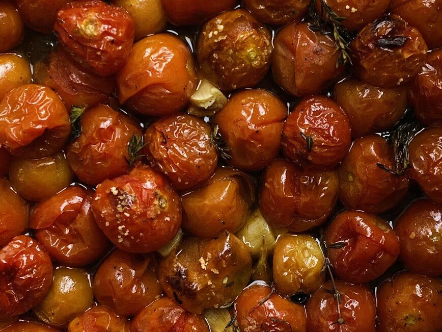 Roasted cherry tomatoes and herbs in a baking pan