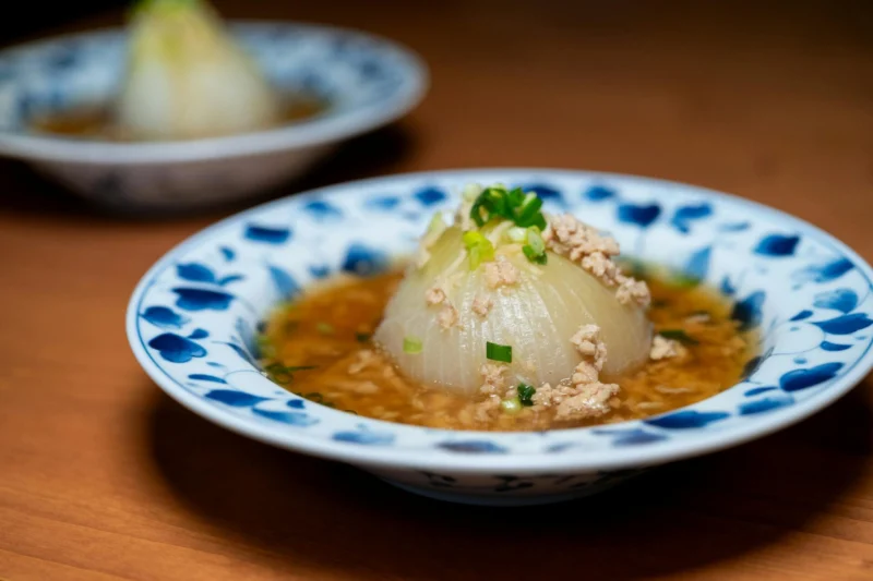 Delicious Japanese onion dish served in a blue floral bowl, garnished with green onions and soy sauce.