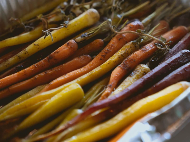 Whole roasted orange and yellow carrots in a baking tray