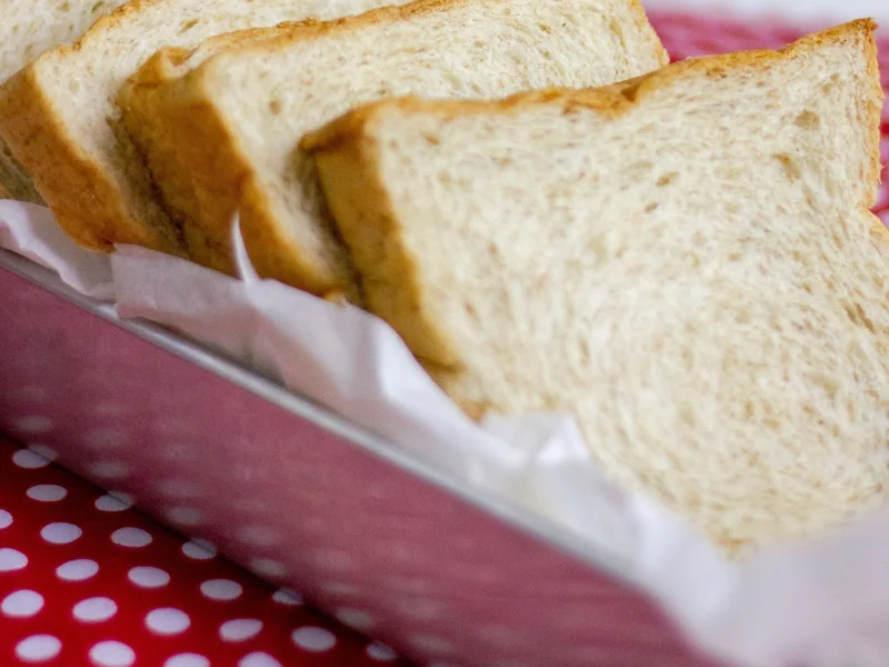 Slices of soft white sandwich bread on a red patterned cloth