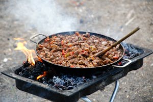 Delicious BBQ meat cooked outdoors on an open fire grill with vibrant peppers.