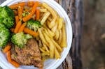 Delicious chicken dinner with broccoli, carrots, and fries on a plate.