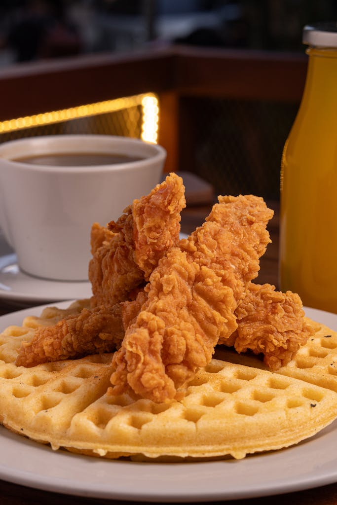 Delicious crispy fried chicken served on warm waffles with a cup of coffee and juice.