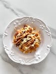 Delicious fusion dish topped with creamy sauces on a decorative white plate, perfect for gourmet dining.