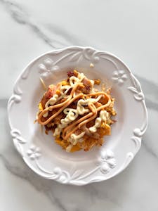 Delicious fusion dish topped with creamy sauces on a decorative white plate, perfect for gourmet dining.