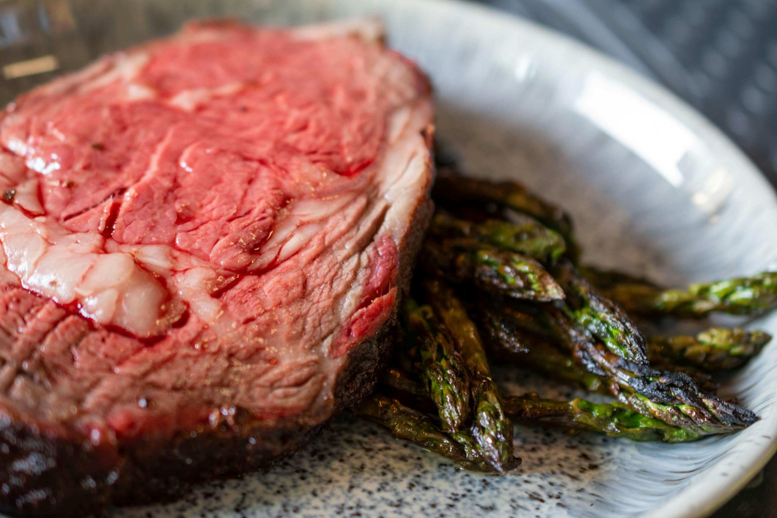 Delicious grilled steak paired with roasted asparagus served on a ceramic plate.