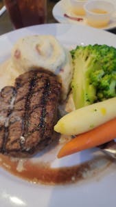 Delicious grilled steak served with mashed potatoes and vegetables in a restaurant setting.