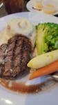 Delicious grilled steak served with mashed potatoes and vegetables in a restaurant setting.