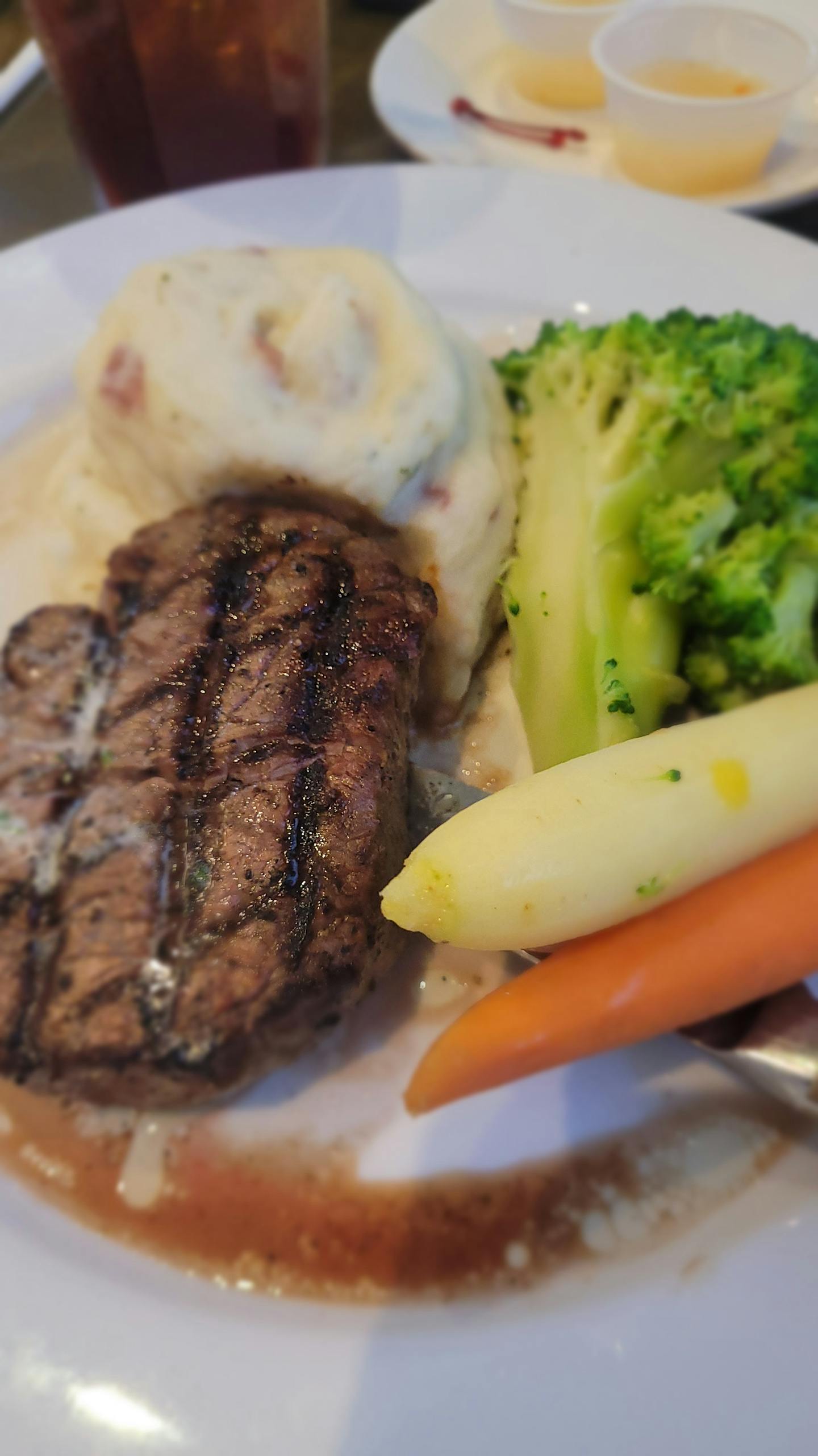 Delicious grilled steak served with mashed potatoes and vegetables in a restaurant setting.