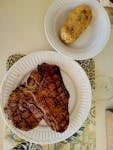Delicious grilled T-bone steak served with a baked potato, perfect for a savory dinner.