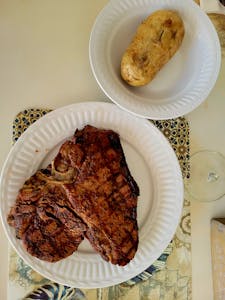 Delicious grilled T-bone steak served with a baked potato, perfect for a savory dinner.