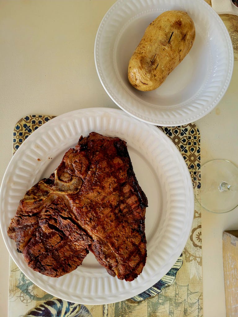 Delicious grilled T-bone steak served with a baked potato, perfect for a savory dinner.