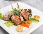 Delicious lamb chops with vegetables plated elegantly on a marble surface.