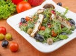 Delicious Mediterranean salad with grilled cheese, olives, and cherry tomatoes on a plate.