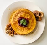 Delicious pancake topped with berry jam, surrounded by almonds and figs, perfect for brunch.