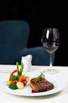 Delicious steak dinner with assorted vegetables and red wine served elegantly in a restaurant setting.