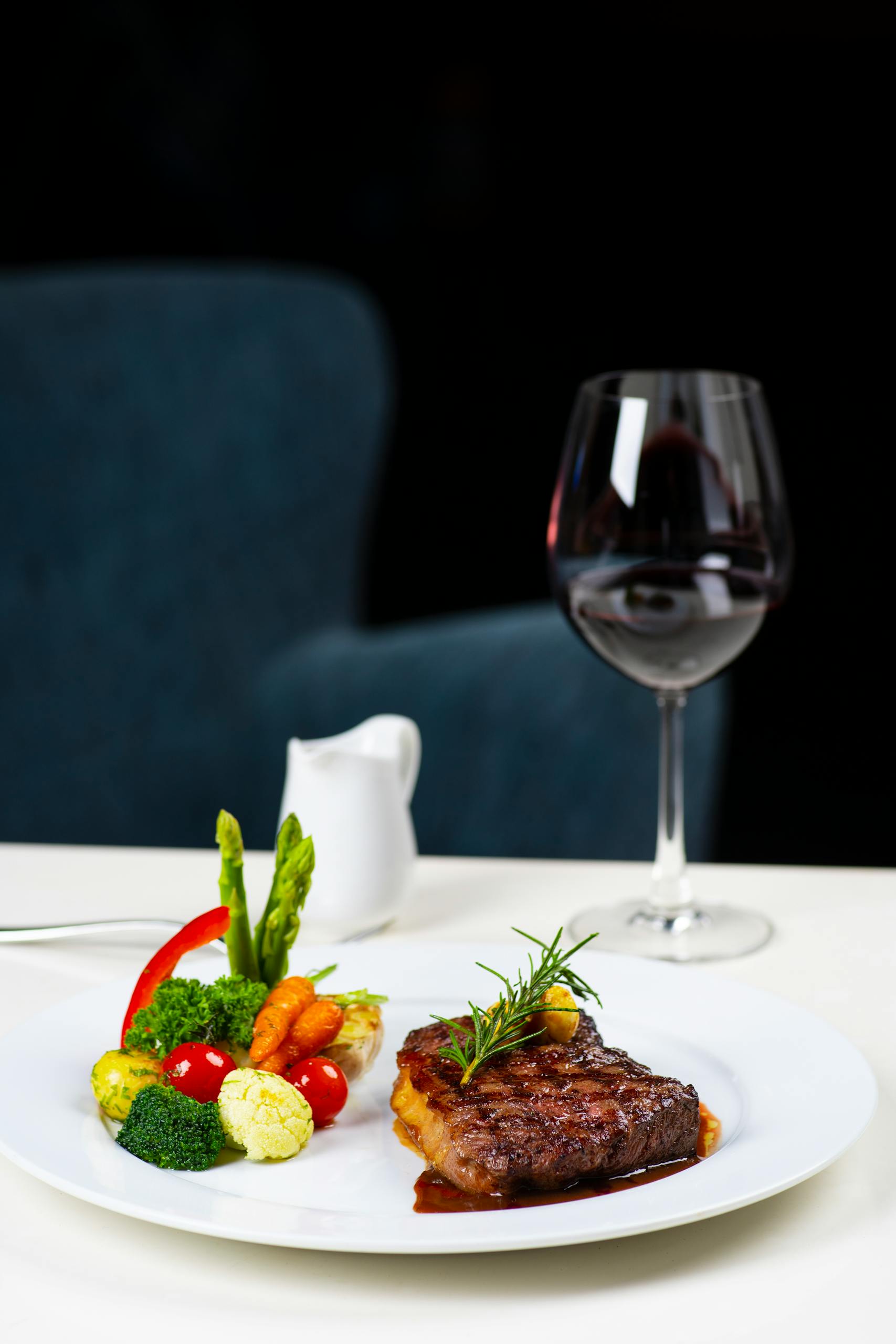 Delicious steak dinner with assorted vegetables and red wine served elegantly in a restaurant setting.