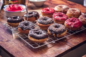 Assorted homemade donuts with chocolate and pink icing on a cooling rack.