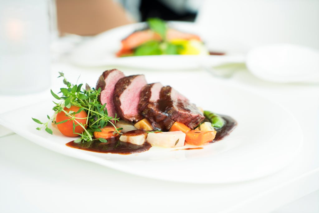 Elegant presentation of sliced beef with herbs and sauce, capturing fine dining ambiance.